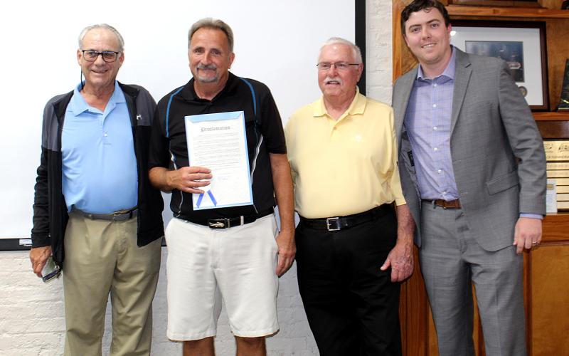 Ron Ferrell, flanked by Friends of the Fernandina Beach Golf Club President Lee Murray and golf club member Mike Meadows, receives a proclamation from Mayor Bradley Bean in recognition for signs he built at the course. Photo by Beth Jones/News-Leader