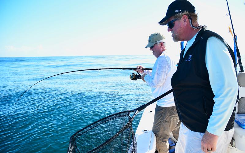 Greg Cook puts a deep bend in his fishing rod, hoping to catch a sizable win-ter cobia, as fellow angler Bill Fassbender waits patiently with his landing net. Submitted photo