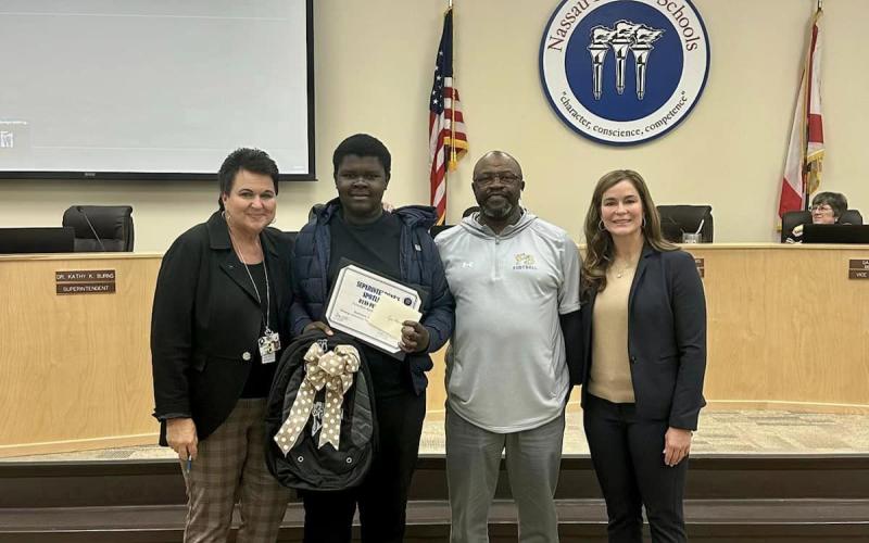 From left, Superintendent of Nassau County School District Kathy Burns, Ryan Peterson, Ryan’s grandfather, Coach Pete, and Anna Crawford, Fernandina Beach Middle School principal, stand with Peterson to share his accomplishments during a recent school board meeting.  Submitted