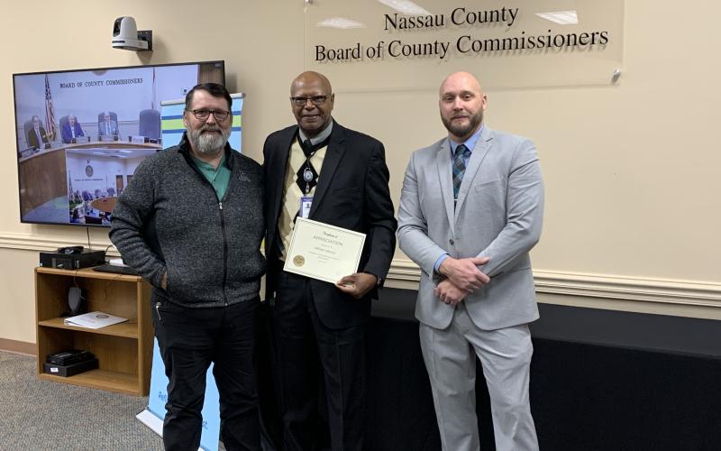 William Johnson, center, of the Road and Bridge Department was acknowledged at Wednesday’s Nassau County Board of County Commissioners meeting for 30 years of service to the county. Presenting the award were Darren Marsh, interim road director, left, and Taco Pope, county manager, right. Photo courtesy of Sabrina Robertson/Nassau County Board of Commissioners