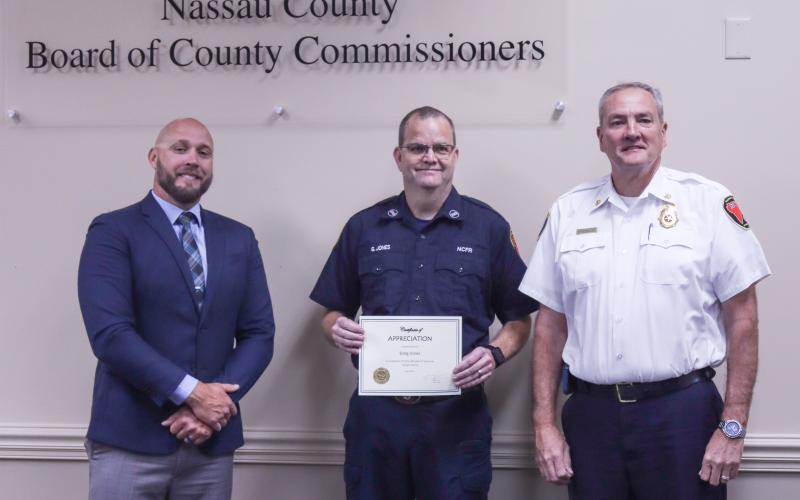 County Manager Taco Pope poses with Greg Jones, who was recognized for 30 years with Nassau County Fire Rescue, and Fire Chief Brady Rigdon at the Nassau County Board of County Commissioners meeting Wednesday morning. Photo by Ashley Chandler/News-Leader