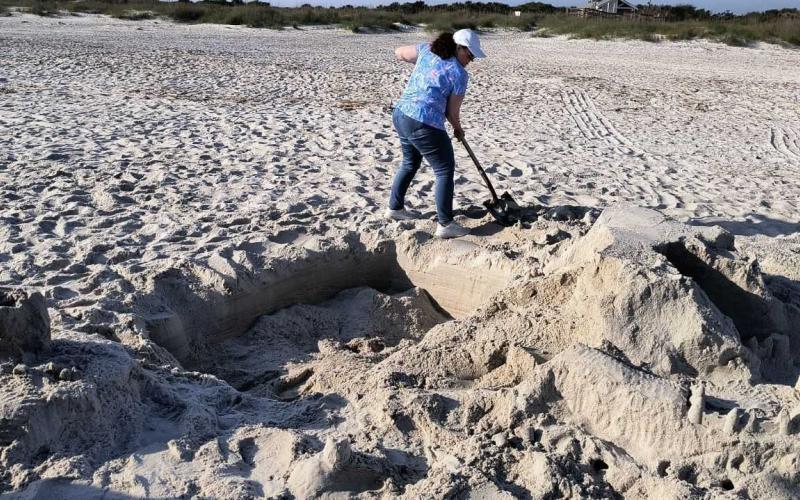 Volunteer Debbie Wasdin fills in a huge hole and flattens a sandcastle two weeks ago at Fort Clinch State Park. Sea turtle advocates say holes have become a huge issue on our beaches. Submitted
